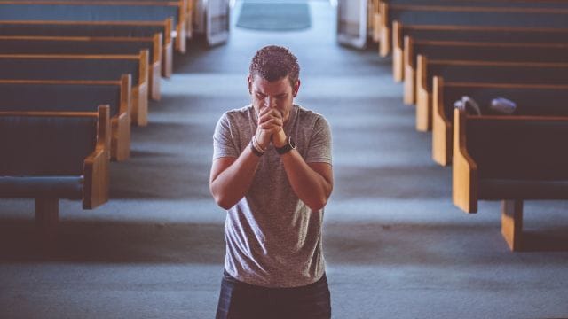 pessoa rezndo em uma igreja