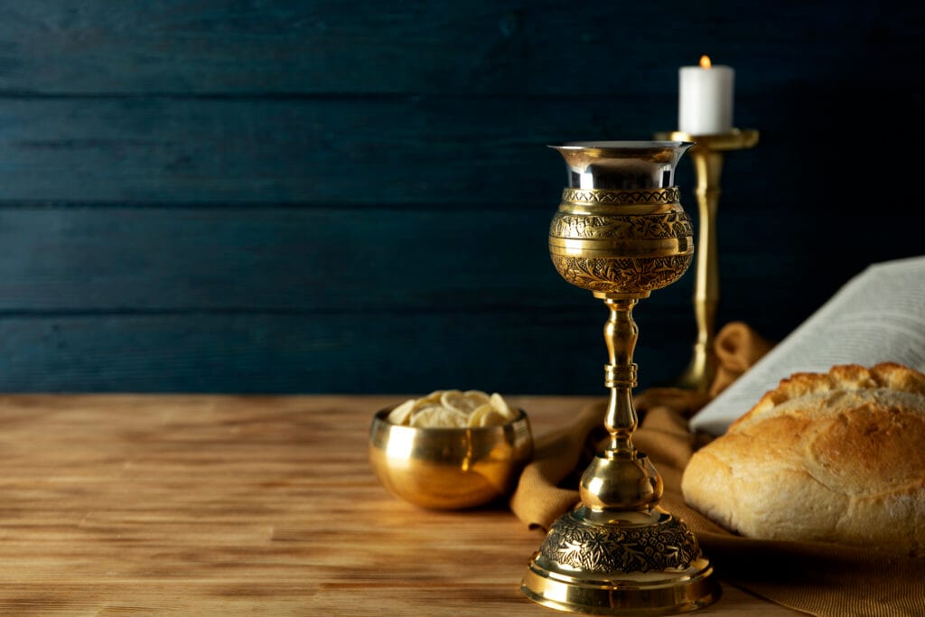 "Imagem de um cálice com vinho e uma hóstia sobre a mesa, representando a Eucaristia na Santa Missa."